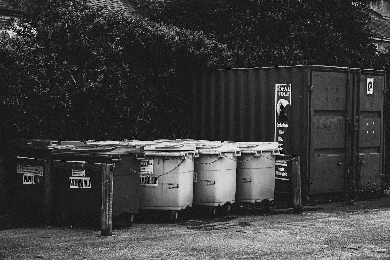 Monochrome image of trash bins and container in an urban setting.