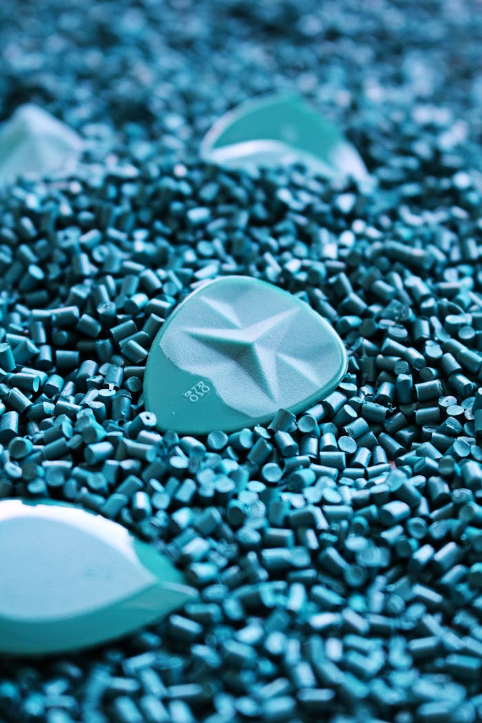 Close-up shot of blue guitar picks surrounded by small plastic pellets, highlighting their textured design.